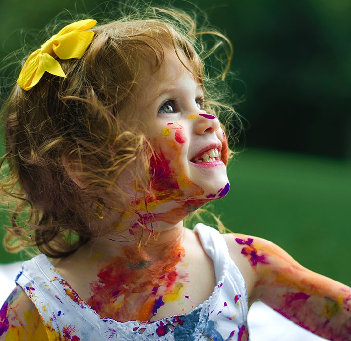happy child with paint streaks on her face and blouse